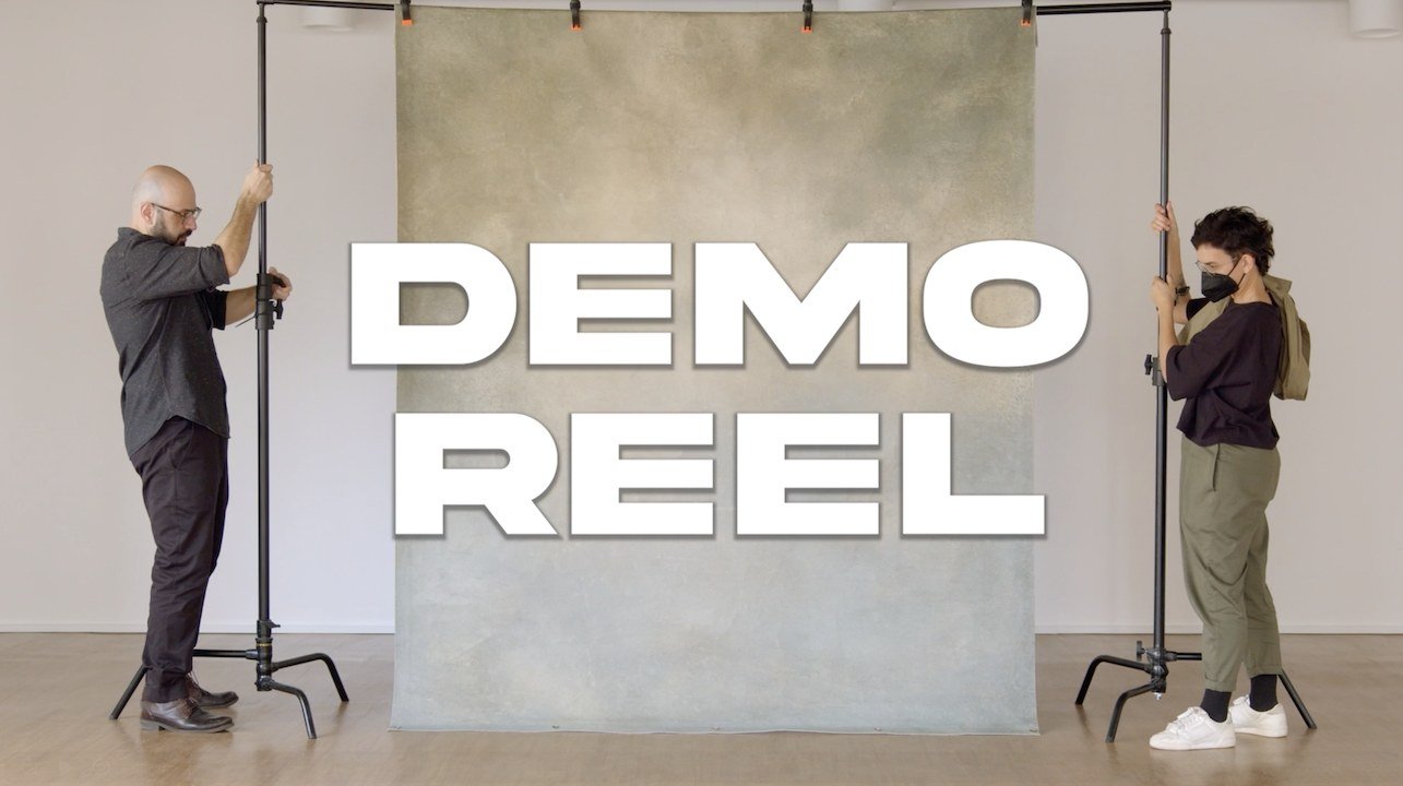 Demo Reel title card in front of a grey backdrop held up by two people